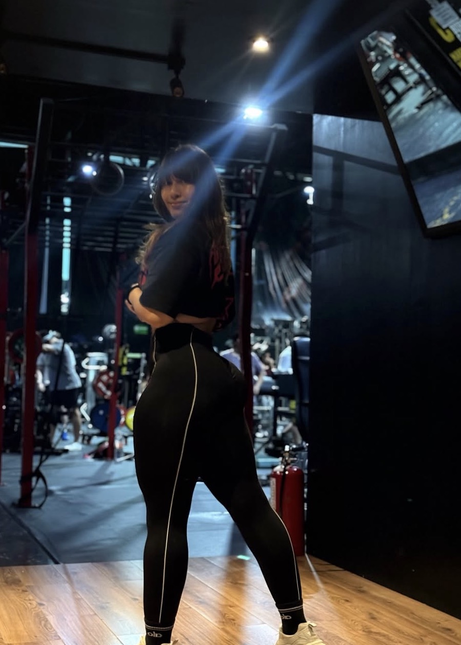 Ara posing in a dimly lit gym